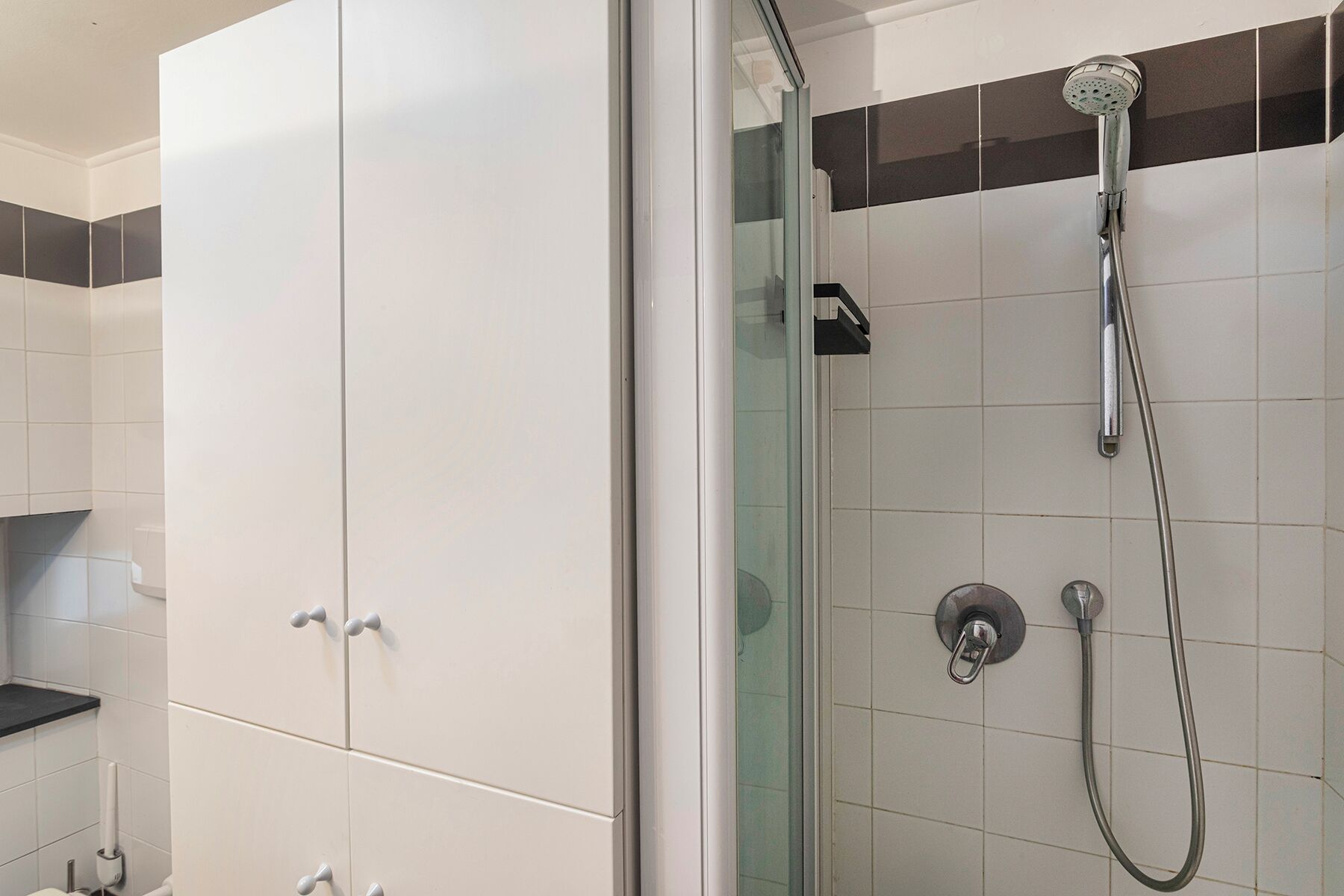 Une salle de bain avec une douche, des toilettes et un meuble de rangement.