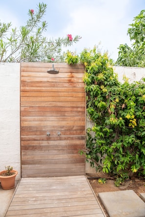 Ein hölzernes Tor führt zu einer Holzterrasse mit einem Blumentopf auf der linken Seite.