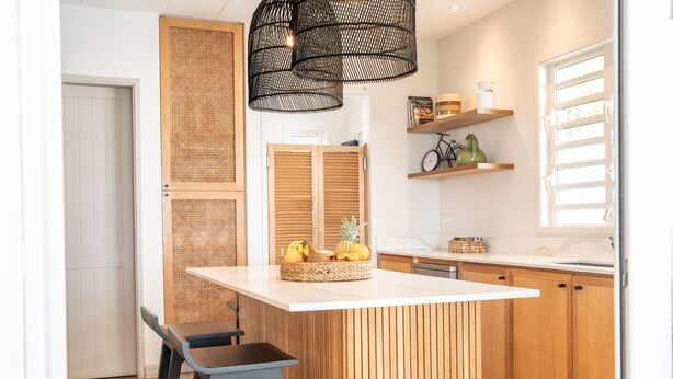 A modern kitchen with a central island, wooden cabinetry, and a hanging light fixture. - Luxury Beachfront Villa • Private Pool, Beach, AC, Calm Lagoon (La Preneuse)