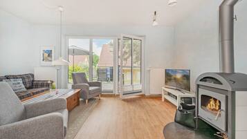 A modern living room with a fireplace, seating area, and a view through the glass door.