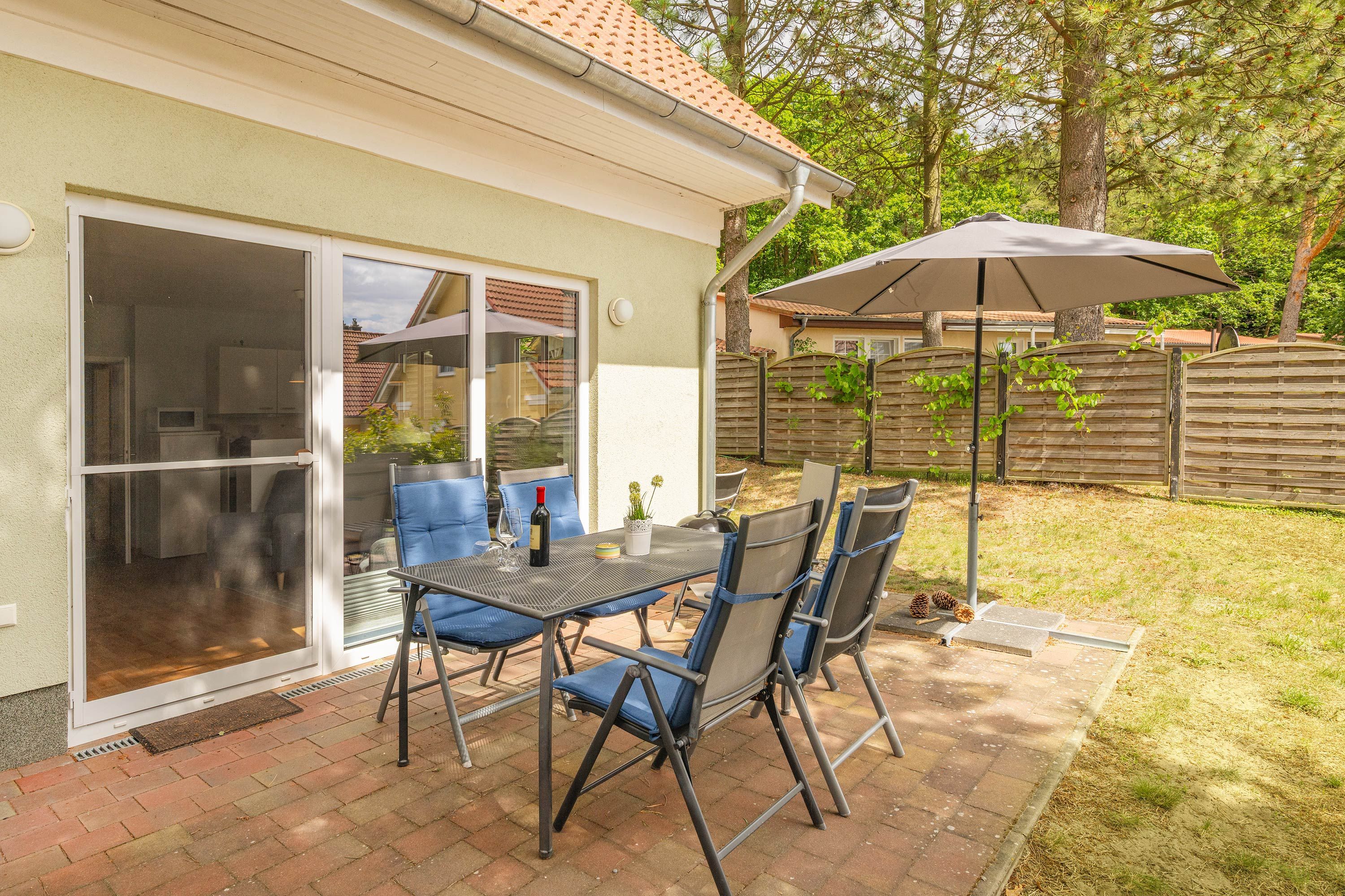 Eine Terrasse mit Tisch und Stühlen, eine Schiebetür und ein überdachter Außenbereich.