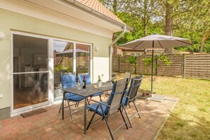 A patio with a table and chairs, a sliding glass door, and a covered outdoor area.