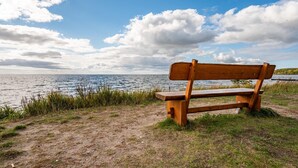 Een houten bank langs een waterpartij met een heldere lucht.