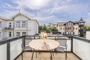 A balcony with a round table and two chairs, overlooking a building with a sign 'Rössli'. - Cozy vacation rental in Ahlbeck near the sea on Usedom (Seebad Ahlbeck)