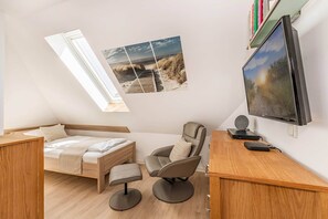 A compact room with a bed, a desk, a chair, and a large TV. - Cozy Vacation Rental in Ahlbeck with Ocean View & Wi-Fi, 1 Parking Space (Seebad Ahlbeck)