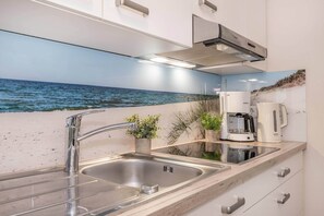 A kitchen with a stainless steel sink, a coffee maker, and a view of the ocean through a large window. - A gorgeous vacation rental in Koserow on the pier, right on the Baltic Sea beach, featuring (Koserow)