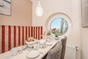 A dining area with a round window, striped wall, and a table set with plates, glasses, and a bread basket. - A gorgeous vacation rental in Koserow on the pier, right on the Baltic Sea beach, featuring (Koserow)