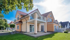 Une maison à deux étages avec un balcon, une allée pavée et une pelouse bien entretenue.