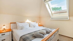 Une chambre à coucher avec un lit, des tables de chevet, une fenêtre et une vue sur les arbres.