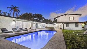 Uma casa moderna com piscina, espreguiçadeiras e um espaço de estar ao ar livre.