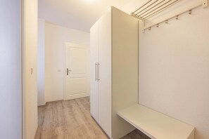 Ein Flur mit einem weißen Schrank, einer Tür und einer Sitzbank.