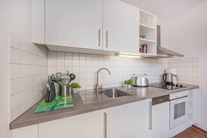 Eine moderne Küche mit weißen Schränken, einer Edelstahl-Spüle und einer Kaffeemaschine.