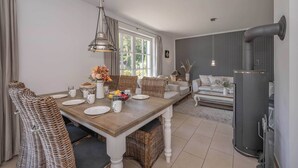 Un comedor con una mesa de madera, sillas de mimbre y una lámpara colgante.
