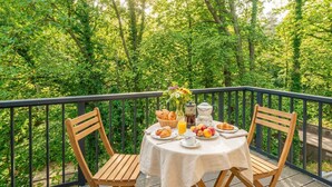A table set on a balcony with chairs, surrounded by lush greenery. - Modern vacation rental in Kölpinsee with a balcony—just 600 m from the beach (Ostseebad Kölpinsee)