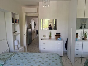 Ein Schlafzimmer mit Bett, Schminktisch, Spiegel und Bücherregal.