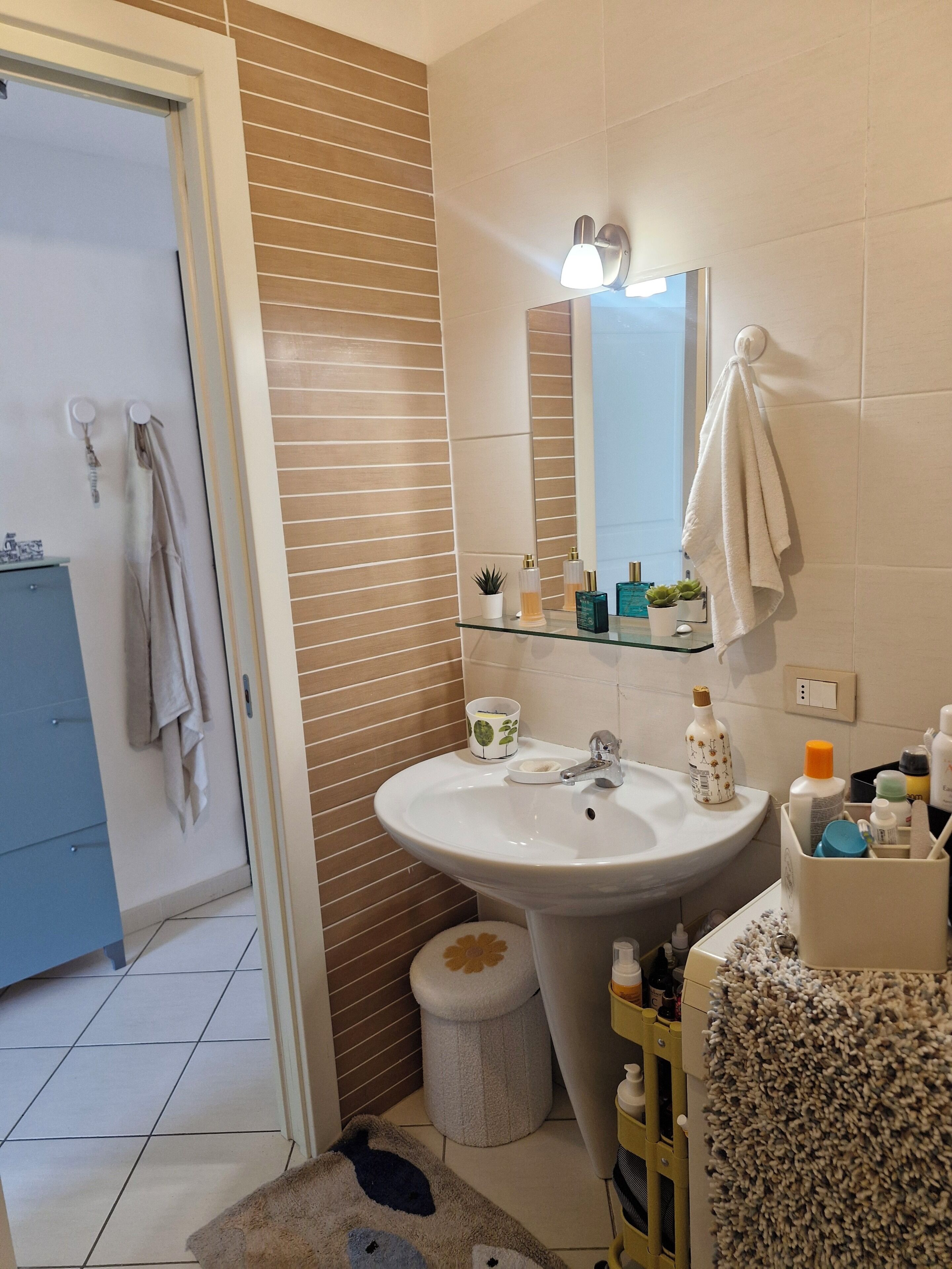 A bathroom with a sink, mirror, towel rack, and toiletries.