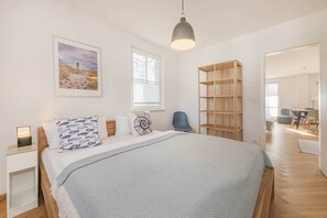 Un dormitorio con cama, mesita de noche, lámpara y un ventanal grande.