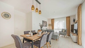 A modern dining area with a wooden table, grey upholstered chairs, and hanging pendant lights. - Modern apartment with a balcony—close to the beach and family-friendly (Ostseebad Kölpinsee)