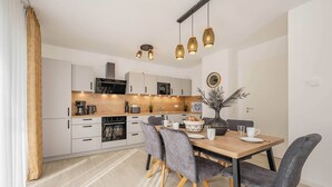 A modern kitchen with white cabinets, a wooden countertop, and a dining area with a table and chairs. - Modern apartment with a balcony—close to the beach and family-friendly (Ostseebad Kölpinsee)