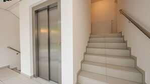 Un ascensor moderno y una escalera con barandilla.