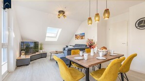 Una sala de estar moderna con un sofá, una mesa de comedor con sillas y un televisor.