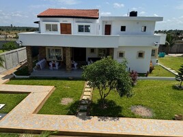 A modern two-story house with a patio area, a small garden, and a paved walkway.