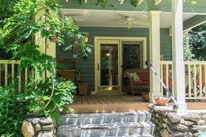 A porch with a wooden deck, a stone wall, and a door leading to the interior.