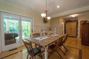 A dining room with a wooden table, chairs, and a chandelier.