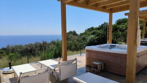 An outdoor patio with lounge chairs, a hot tub, and a pergola overlooking a scenic view. - Deluxe Apartment in Casal Trinacria with a Jacuzzi (Sicilia)