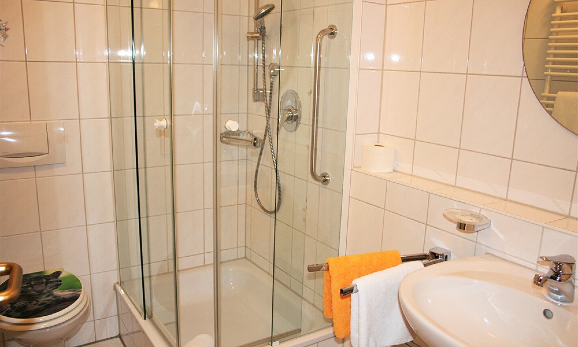 A bathroom with a glass-enclosed shower, a toilet, and a sink with a mirror.