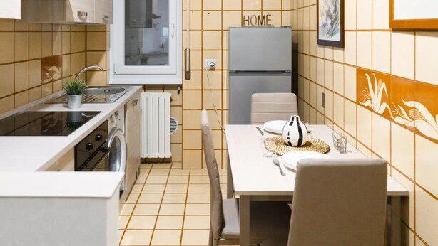 A compact kitchen with a sink, stove, and refrigerator, a dining table with chairs, and a window. - AG19 • Apartment in downtown Milan • (Milano)