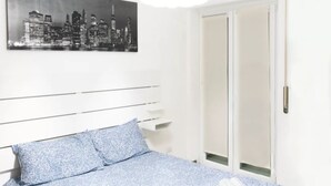 A bedroom with a bed, pillows, a cityscape painting, and a sliding door. - AG19 • Apartment in downtown Milan • (Milano)