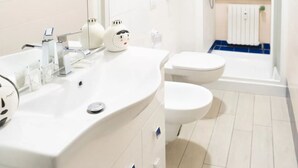 A bathroom with a white sink, a mirror, a toilet, and a bathtub. - AG19 • Apartment in downtown Milan • (Milano)