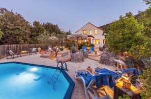 En swimmingpool, solstolar, ett trädäck och ett hus i bakgrunden.