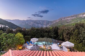 A rooftop pool area with a view of mountains, surrounded by trees and equipped with lounge chairs and umbrellas. - Charming 4-Bedroom Stone Villa with Pool & Garden, 15 Min to Dubrovnik (Knežica)