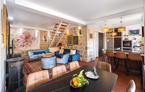 A modern interior with a stone wall, a staircase, a dining area with a black table, and a kitchen with bar stools. - Charming 4-Bedroom Stone Villa with Pool & Garden, 15 Min to Dubrovnik (Knežica)