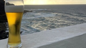 A glass of beer on a ledge with a view of the ocean and a cloudy sky. - Apartamento con Vistas al Ocenao Atlantico (Santa María de Guía de Gran Canaria)