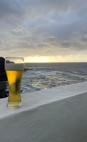 A glass of beer on a ledge with a view of the ocean and a cloudy sky. - Apartamento con Vistas al Ocenao Atlantico (Santa María de Guía de Gran Canaria)