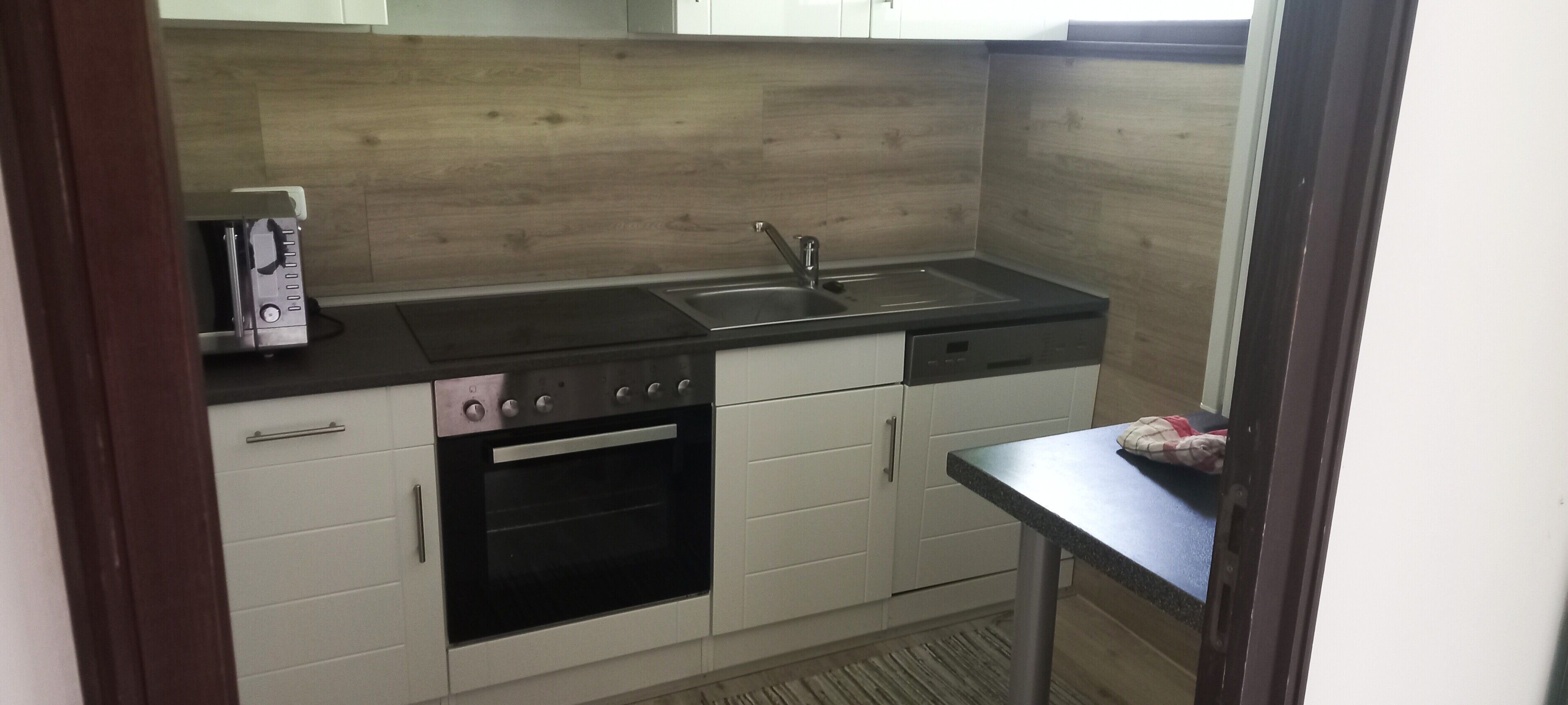 A compact kitchen with a built-in oven, a dishwasher, and a double sink.
