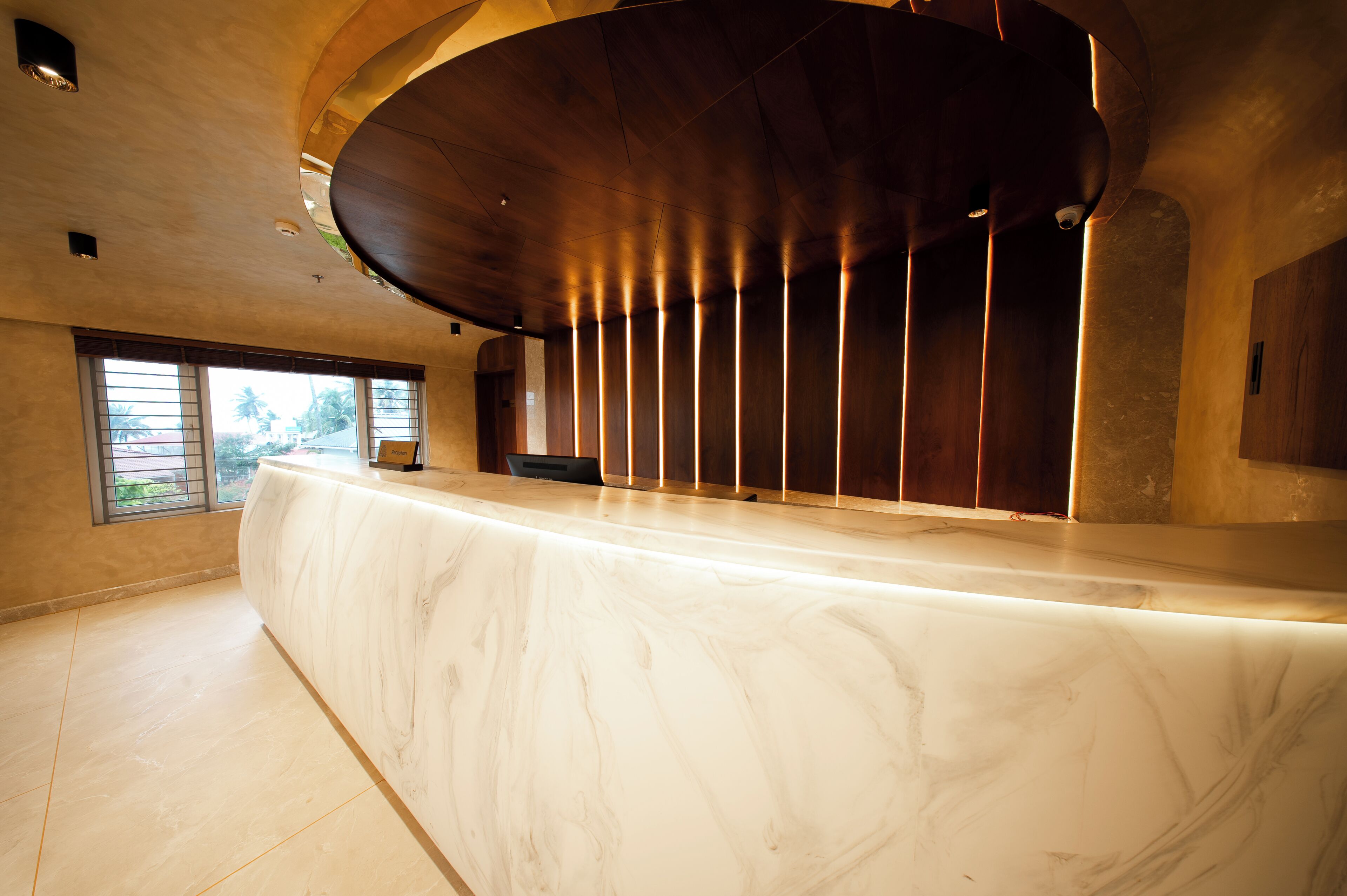 A reception desk with a marble top, a curved wooden ceiling, and a view of the outdoors through a window.