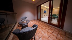 Un balcón con mobiliario de mimbre, una puerta corrediza de vidrio que da a un espacio interior y una lámpara de techo.