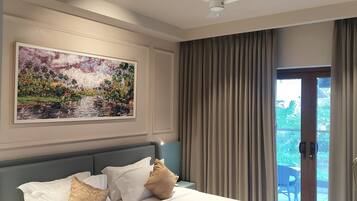 Un cuarto de hotel con una cama, una mesita de noche, una lámpara, un cuadro y vistas a través del ventanal.