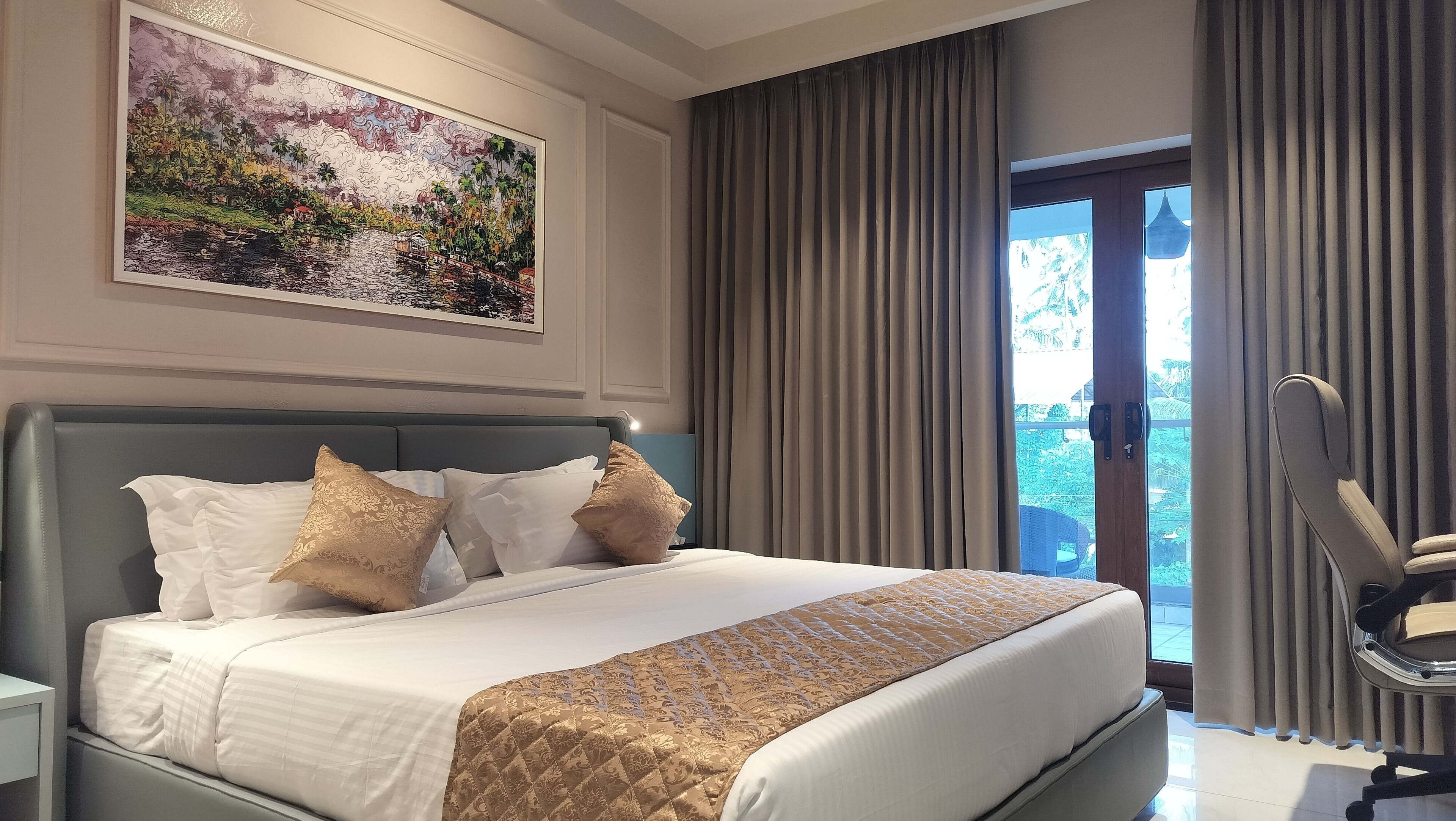 Hotelkamer met een groot bed, een hoofdeinde, een schilderij aan de muur en uitzicht door de gordijnen.