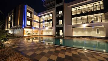 A hotel with a pool, checkered floor, and modern architecture.