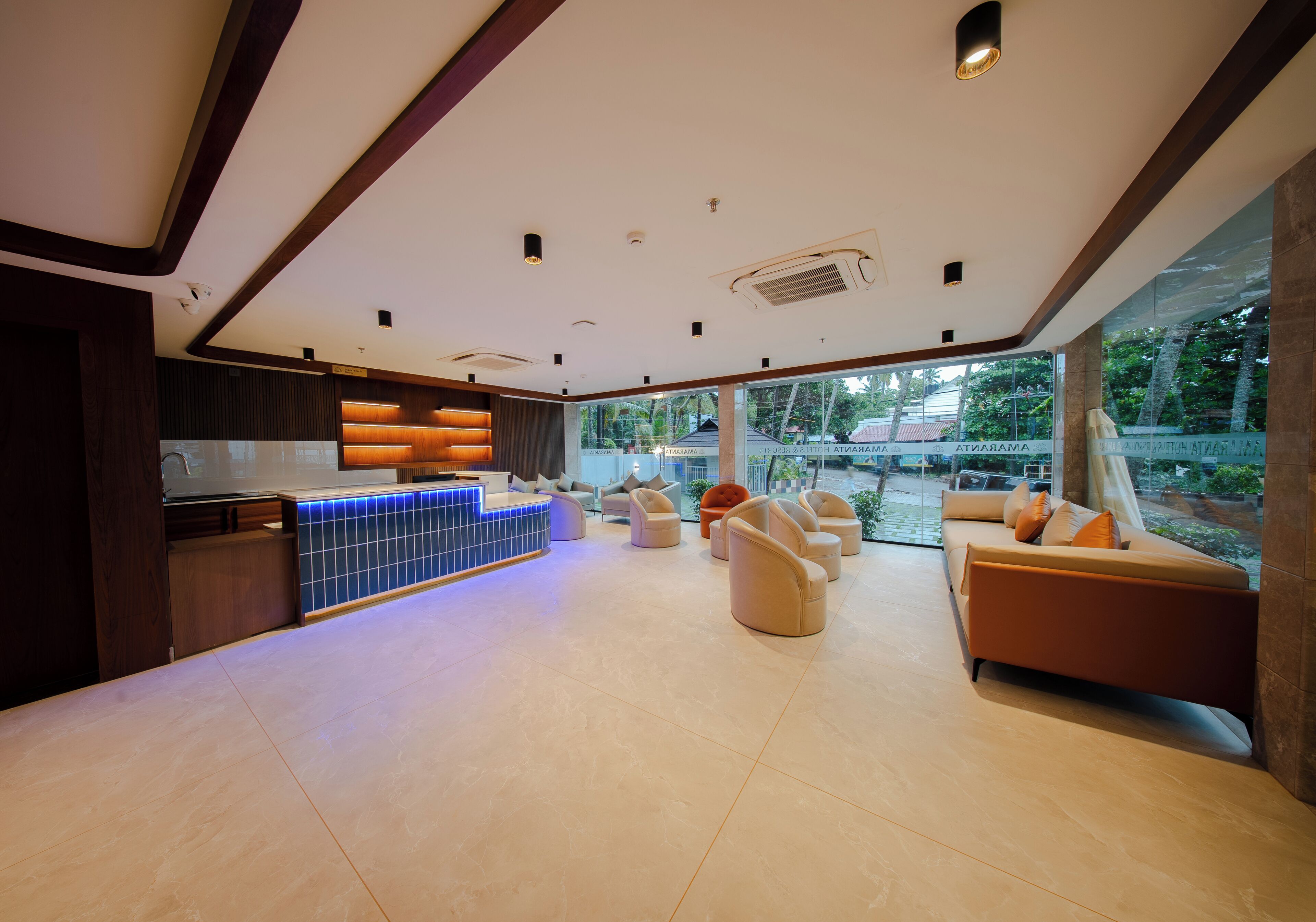 Un amplio vestíbulo de hotel con mostrador de recepción, zona de estar y grandes ventanales que ofrecen vistas al exterior.