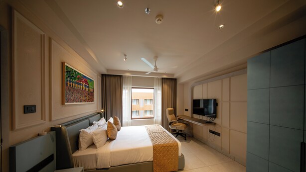 Una habitación de hotel con cama, escritorio con computadora, televisor y armario.