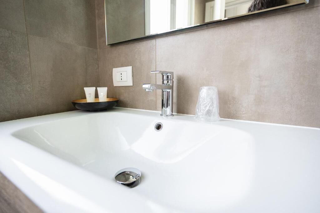 Un baño moderno con un lavamanos grande blanco, grifo cromado y un espejo encima.