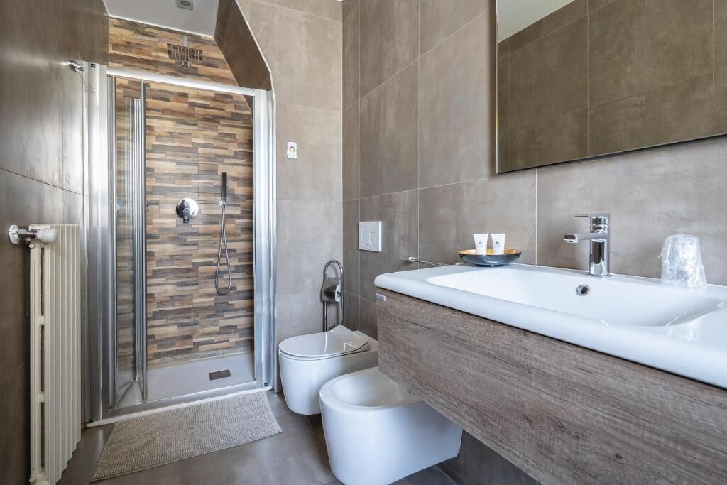 A modern bathroom with a shower, toilet, and sink.