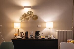 Una camera d'hotel con una scrivania in legno scuro, due lampade a parete, un elemento decorativo al muro e un termosifone.