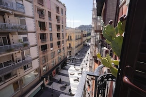 Un edificio a più piani con balconi, un cortile interno e una pianta di cactus.
